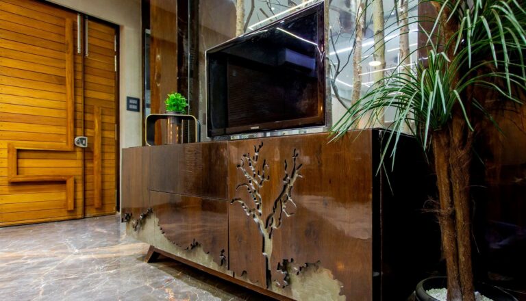 Modern lobby with a wooden reception desk, potted plants, and a television.