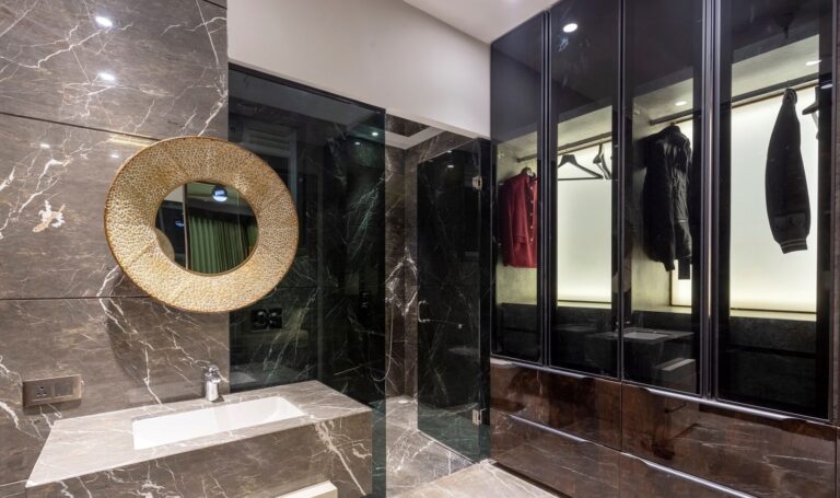 Modern bathroom with marble walls, a textured mirror, and a glass-enclosed shower.